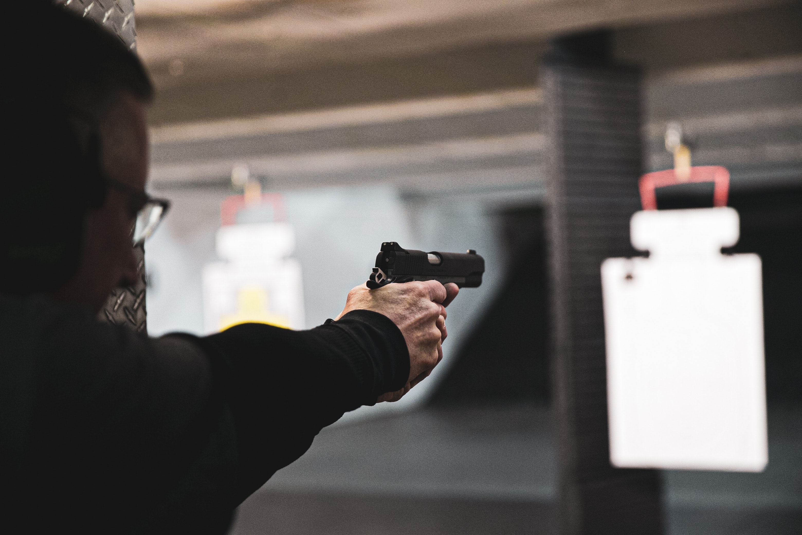 man in firing range shooting a hand gun at target